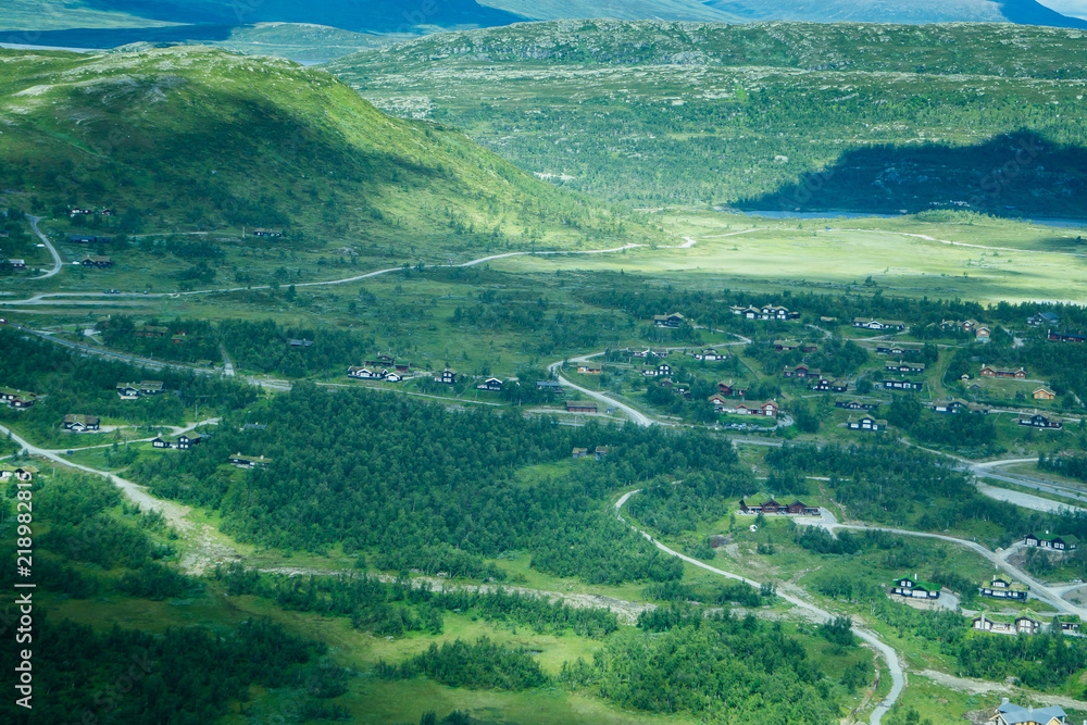 A summer landscape of a village and mountains from a birds eye view.
