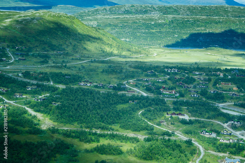 A summer landscape of a village and mountains from a birds eye view.