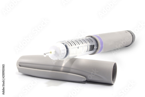 Insulin pen with insulin drop at needle tip isolated on white background. Medical devices is used to self-injection for treatment diabetes disease. World diabetes day and health care concept.