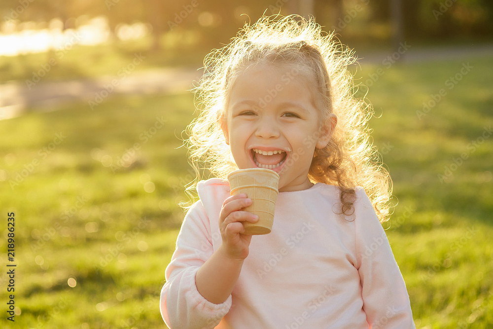 happy and little girl eating ice cream in summer park - obrazy, fototapety, plakaty 