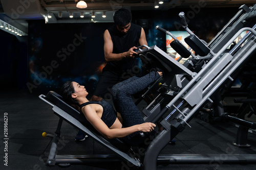 Fit woman working out with trainer at the gym, Woman doing muscle training at the gym. Athlete working out at the gym by pulling weight.