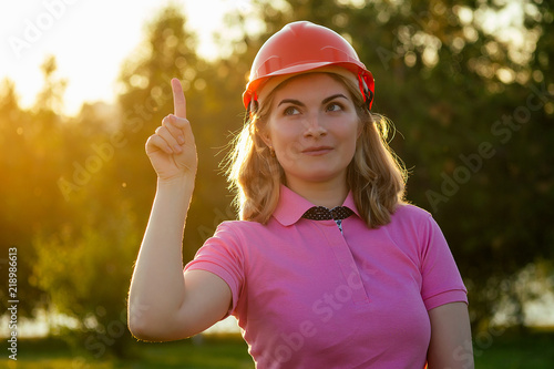 happy woman putting on a helmet hard hat in summer park, career guidance idea