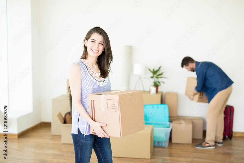 Female Owner Smiling And Carrying Box In New House Female Owner Smiling And Carrying Box In New House