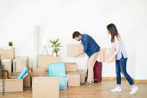 Couple Stacking Cardboard Boxes On Hardwood Floor In New House © AntonioDiaz