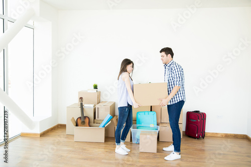 Couple Lifting Heavy Cardboard Box While Setting Up New Home © AntonioDiaz