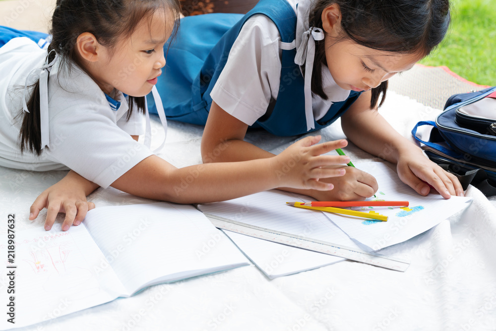 two sister girl writes to writing-books. The decision of lessons. girl lay down drawing the picture two sister girl writes to writing-books. The decision of lessons. girl lay down drawing the picture