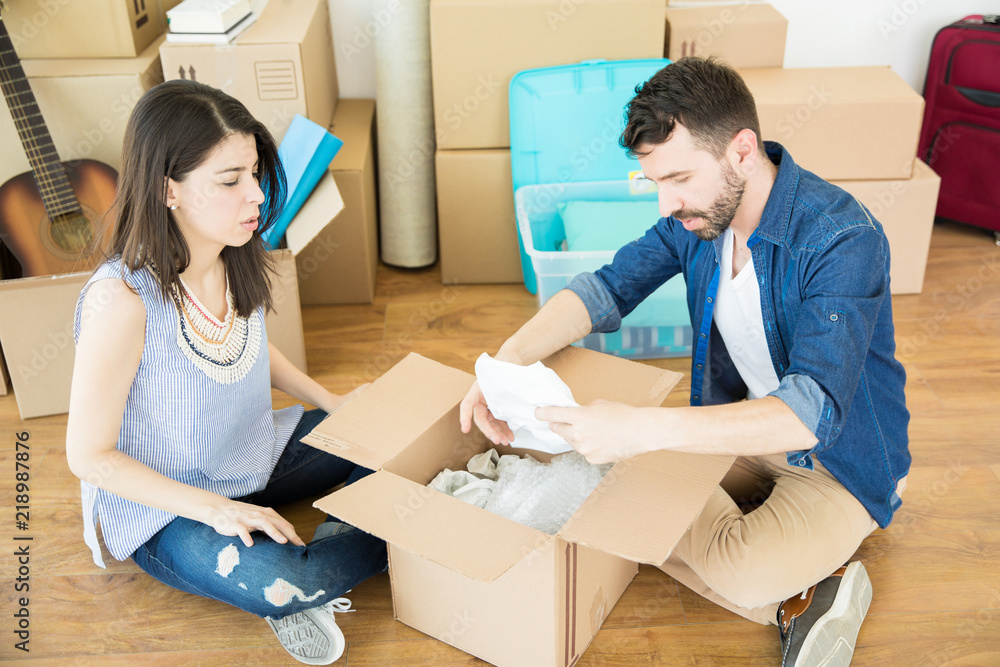Fototapeta premium Couple Taking Out Stuff From Corrugated Box In New Home