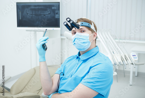 Young handsome dentist man wearing uniform holding equipment looking at the camera