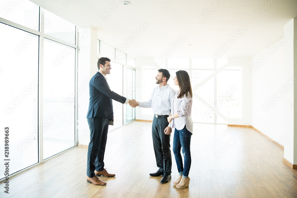 Fototapeta premium Agent Shaking Hands With Man By Woman In New Home