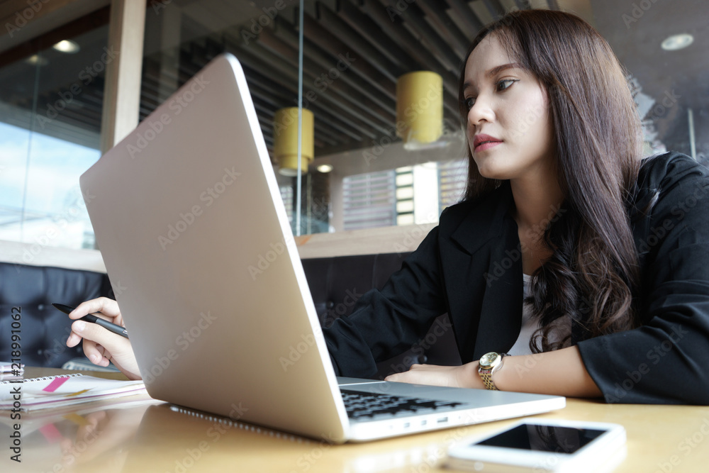 Asian businesswoman sitting at sofa working Laptop on table in coffee shop Asian businesswoman sitting at sofa working Laptop on table in coffee shop