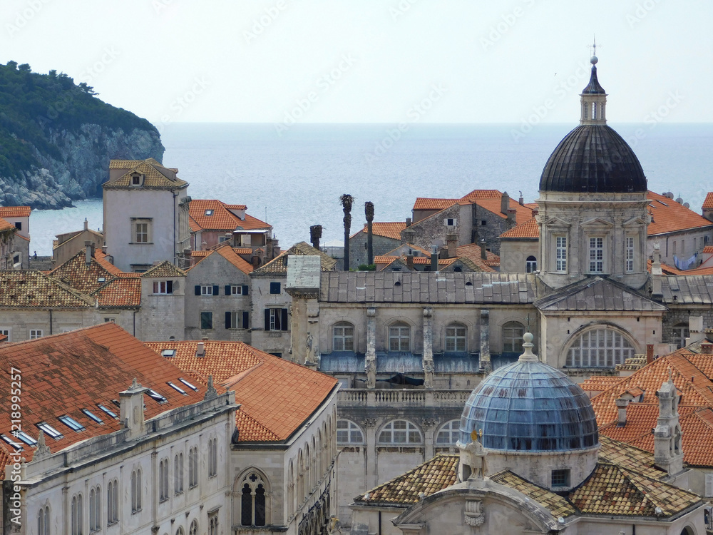 View of Dubrovnik, historic Old Town with buildings and red roofs on the background of the sea, sky, nearby island, Croatia