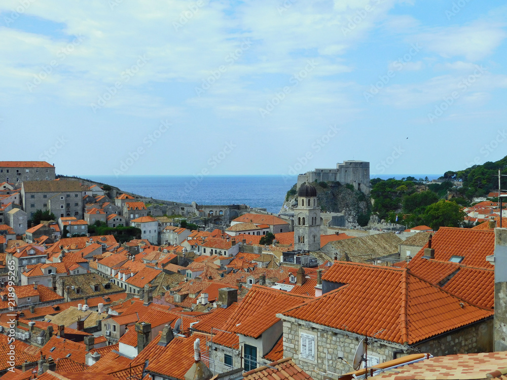 View of Dubrovnik, historic Old Town with buildings and red roofs on the background of the sea, sky, nearby island, Croatia