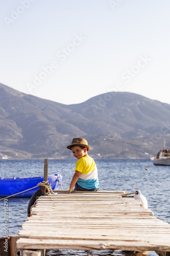 Little boy on a dock sitting on his back looking to the ocean