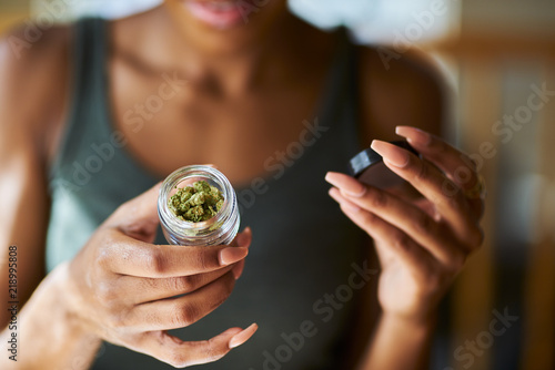 african american woman opening bottle of legal marijuana from dispensary close up photo