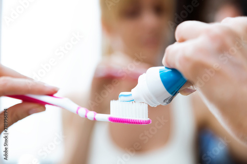 Beautiful young woman holding her tooth-brush with toothpaste at home.