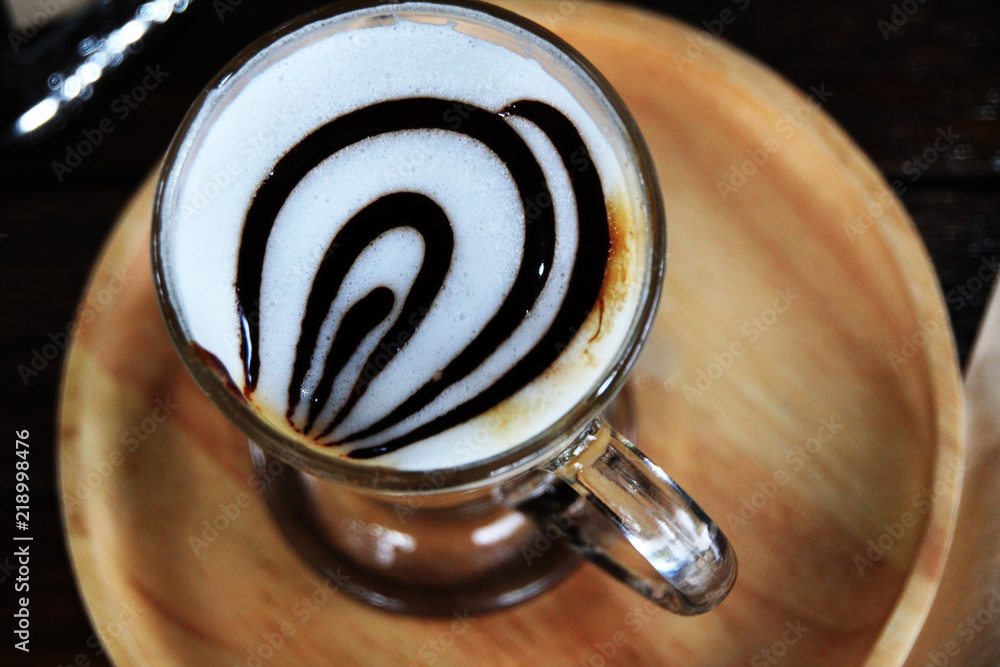 Hot coffee with caramel in the glass put on the wood tray. Hot coffee with caramel in the glass put on the wood tray.