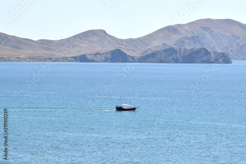 старинное морское судно плывет в бухте на фоне гор. Коктебель. Крым.