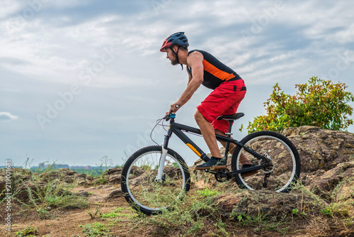 Cyclist on a mountain bike riding on the rock, free space for your text.