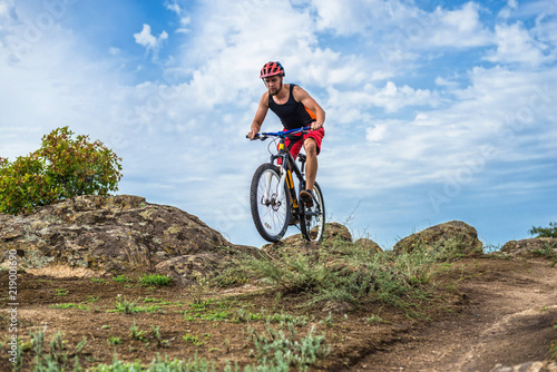 Cyclist riding down the rock on a mountain bike, extreme enduro cycling.