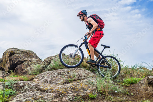 Cyclist descending down the rock on a mountain bike, an active lifestyle.