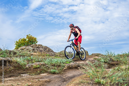 Cyclist in a helmet and with a backpack riding down the rock on a mountain bike  an active lifestyle.