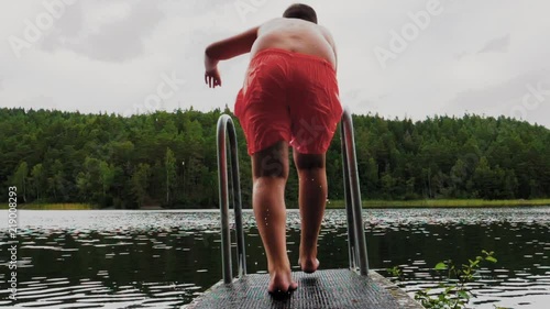 Unrecognizable kid diving into lake on a cloudy evening