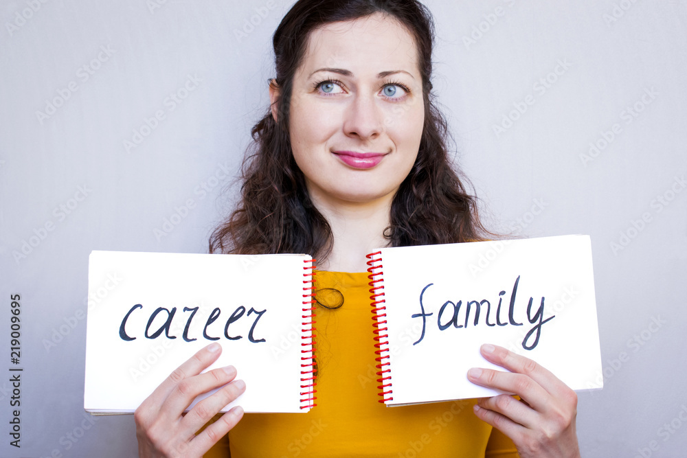 Young woman holding notebooks with written words Career and Family, choice concept. Young woman holding notebooks with written words Career and Family, choice concept.