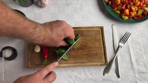 Home chef chopping basil for an italian style tomato salad photo