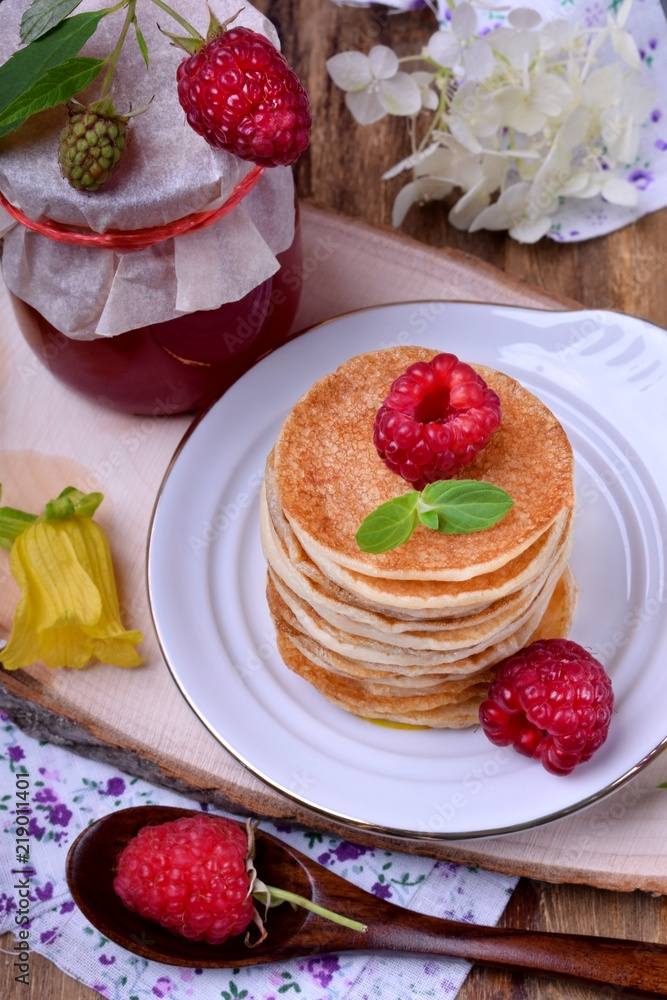Stack of pancakes decorated with raspberry and mint on a white plate. Village style Stack of pancakes decorated with raspberry and mint on a white plate. Village style