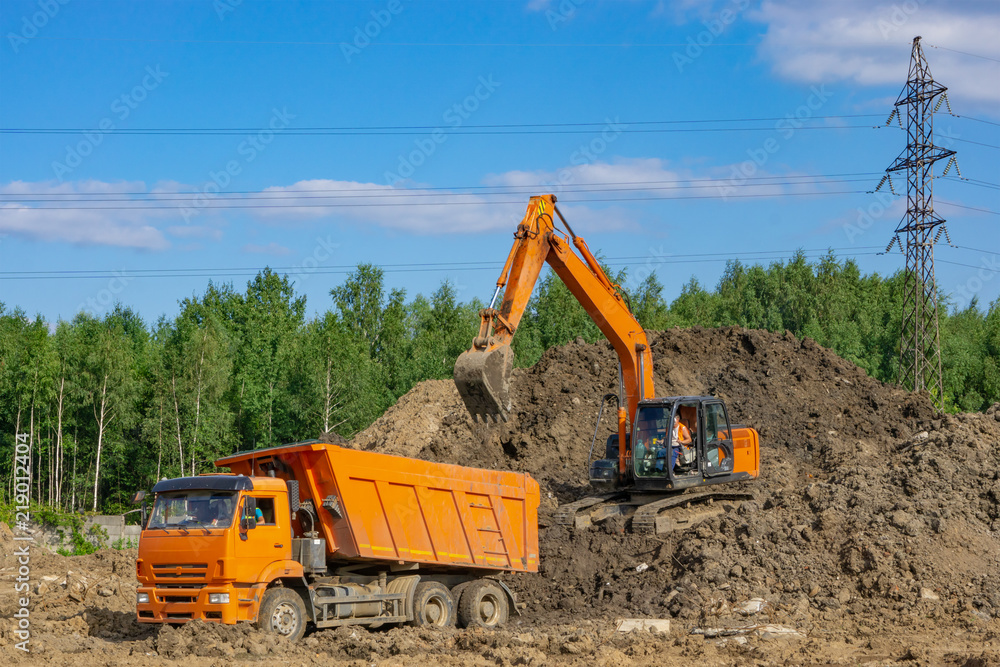 Orange excavator loads the soil in an orange truck Orange excavator loads the soil in an orange truck