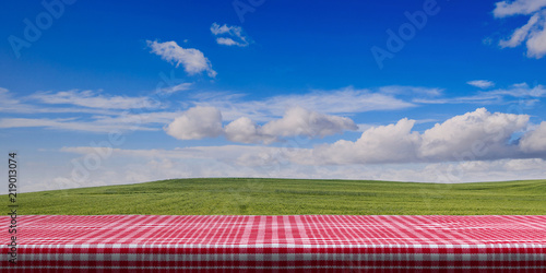 Table covered with red tablecloth on blue sky background, copy space. 3d illustration