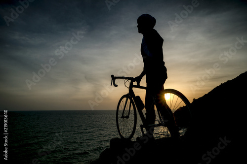 Fototapeta Naklejka Na Ścianę i Meble -  Biker silhouette riding along beach at sunset