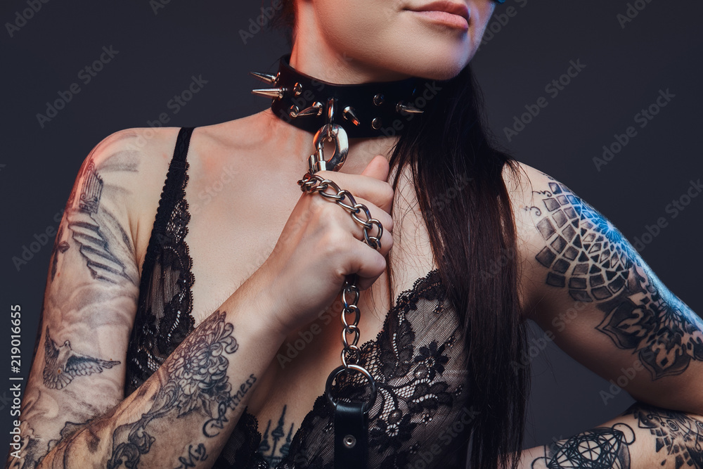 Sexy woman wearing black lingerie in BDSM cat leather mask and accessories posing on dark background. 