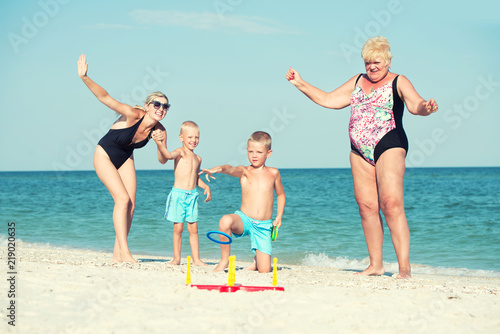 Children together with their mother and grandmother playing a game throwing rings on the beach