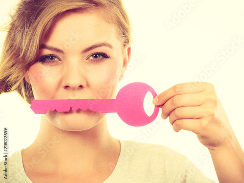 Teenage girl with braid holding key on lips