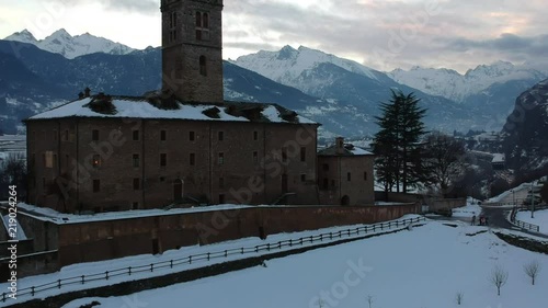 Flying Up Over Fenis Castle in Italy Revealing The Snow Covered Alps in Winter photo