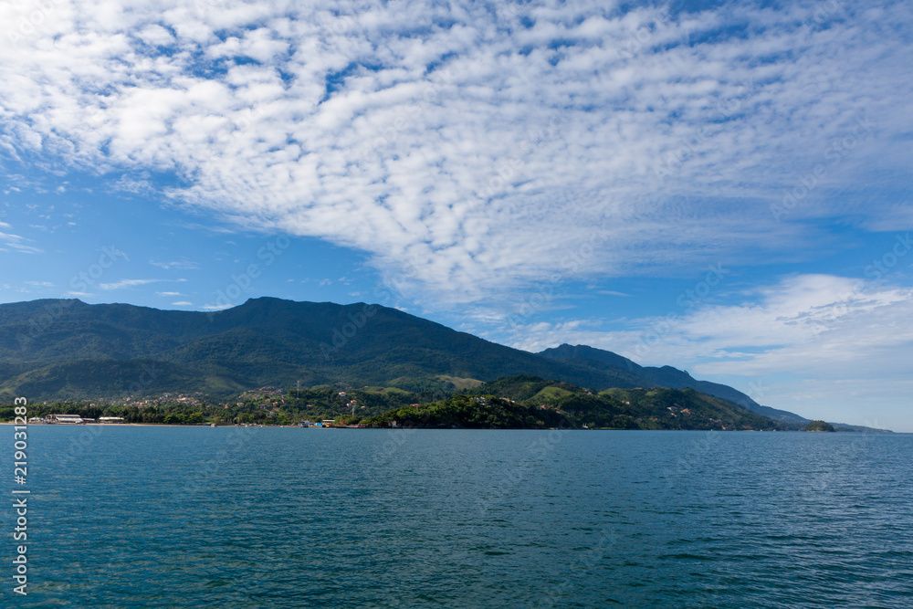 Panoramic view with sea, mountain and blue sky on sunny summer day in Ilha Bela on the coast of São Paulo, Brazil.