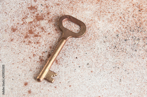 Old bronze key on concrete background.