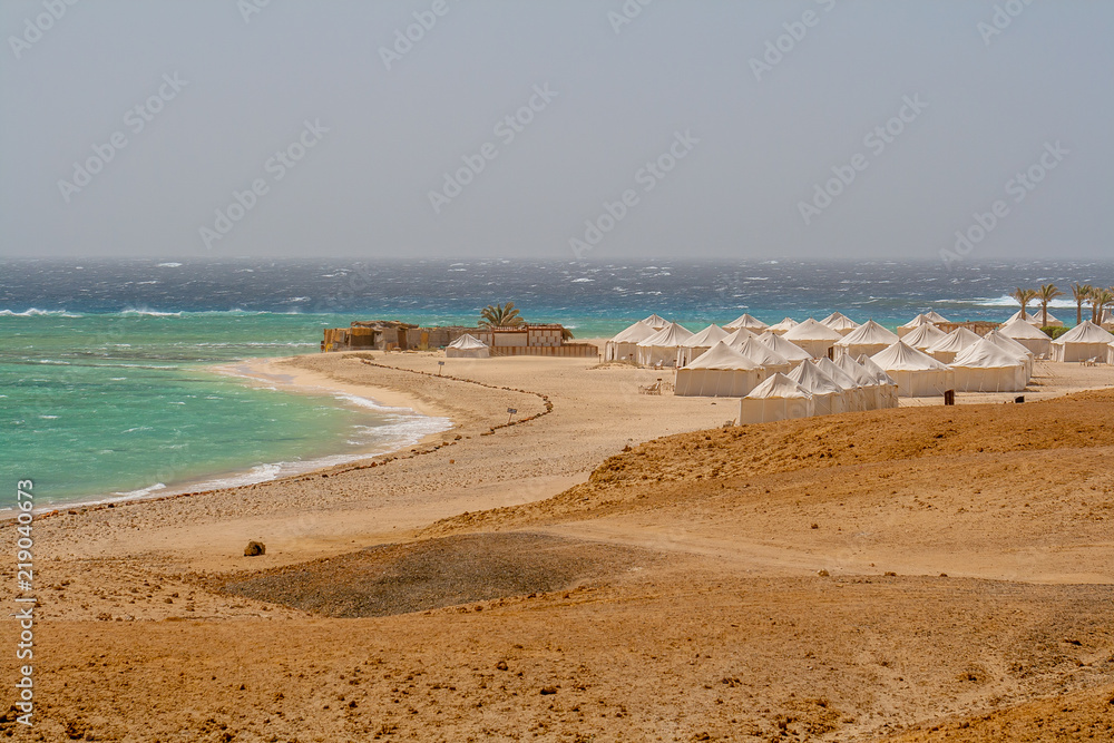 View of Wild Waves Crashing Over Coral Reef and Bedouin Tents in Wind on Beach in Marsa Alam
