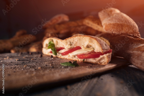 fresh sandwich with tomato, basil and mozzarella on wood;