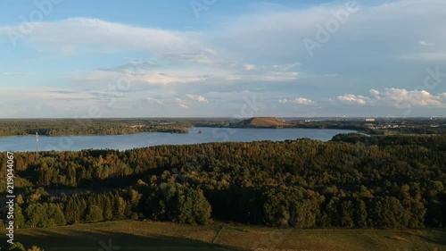 Flying over a little forest near a motorway and other roads with few houses and a lake photo