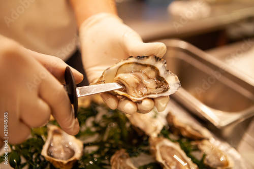 Chef shuck fresh oysters with knife. Raw oysters are packed with nutrition, high in calcium, potassium, magnesium, vitamin and mineral. Flavor are sweet and refreshing. Believed to be an aphrodisiac.