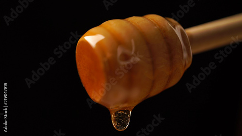 organic honey dripping from wooden honey spoon background
