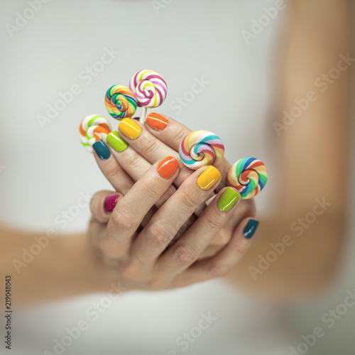 Wallpaper Mural Beautiful woman hands with rainbow nail polish holding colorful swirl lollypops, funny cheerful, can be used as background  Torontodigital.ca