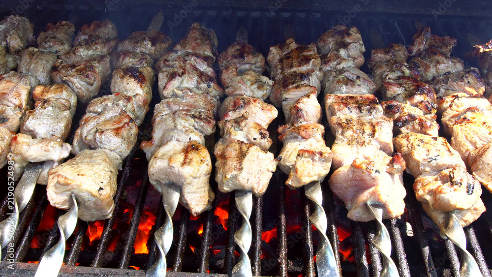 Juicy roasted chicken skewers,made of white meat and bacon, being turned on the bbq