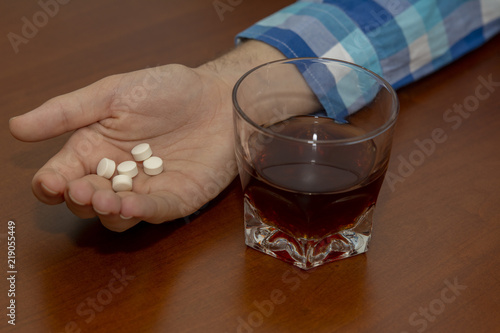 mano de hombre con  drogas y vaso de alcohol, después del abuso de alcohol y drogas photo
