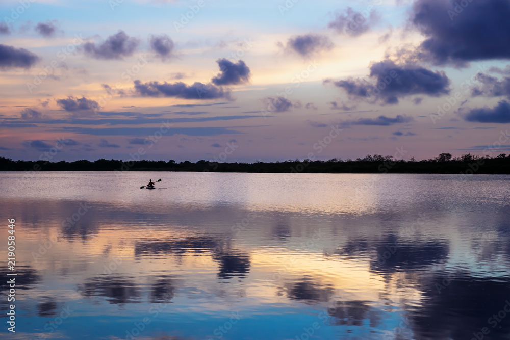 Kanu in the middle of lagoon during purple sunset in Utila, Honduras, Central America