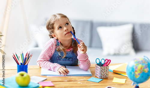 child girl doing homework writing and reading at home