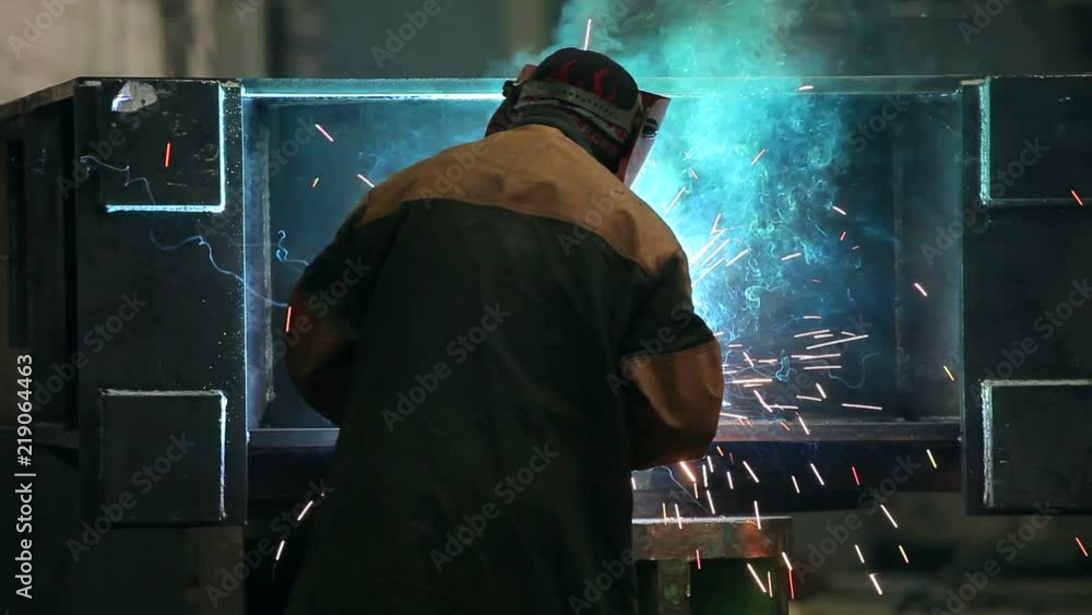 Welder in protective helmet works at factory Welder in protective helmet works at factory