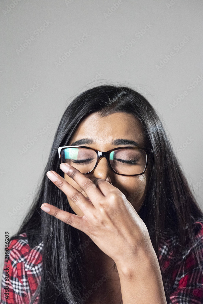 Studio portrait of young woman pinching nose, sneezing Studio portrait of young woman pinching nose, sneezing